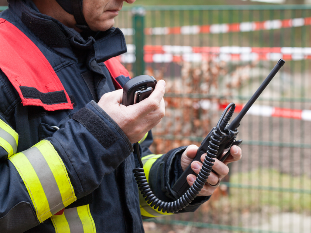 An emergency responder speaks into a hand held radio