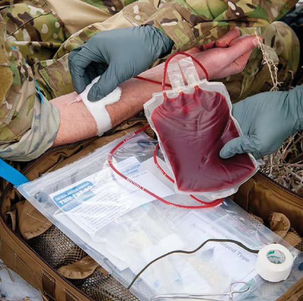 Military members perform a blood transfusion
